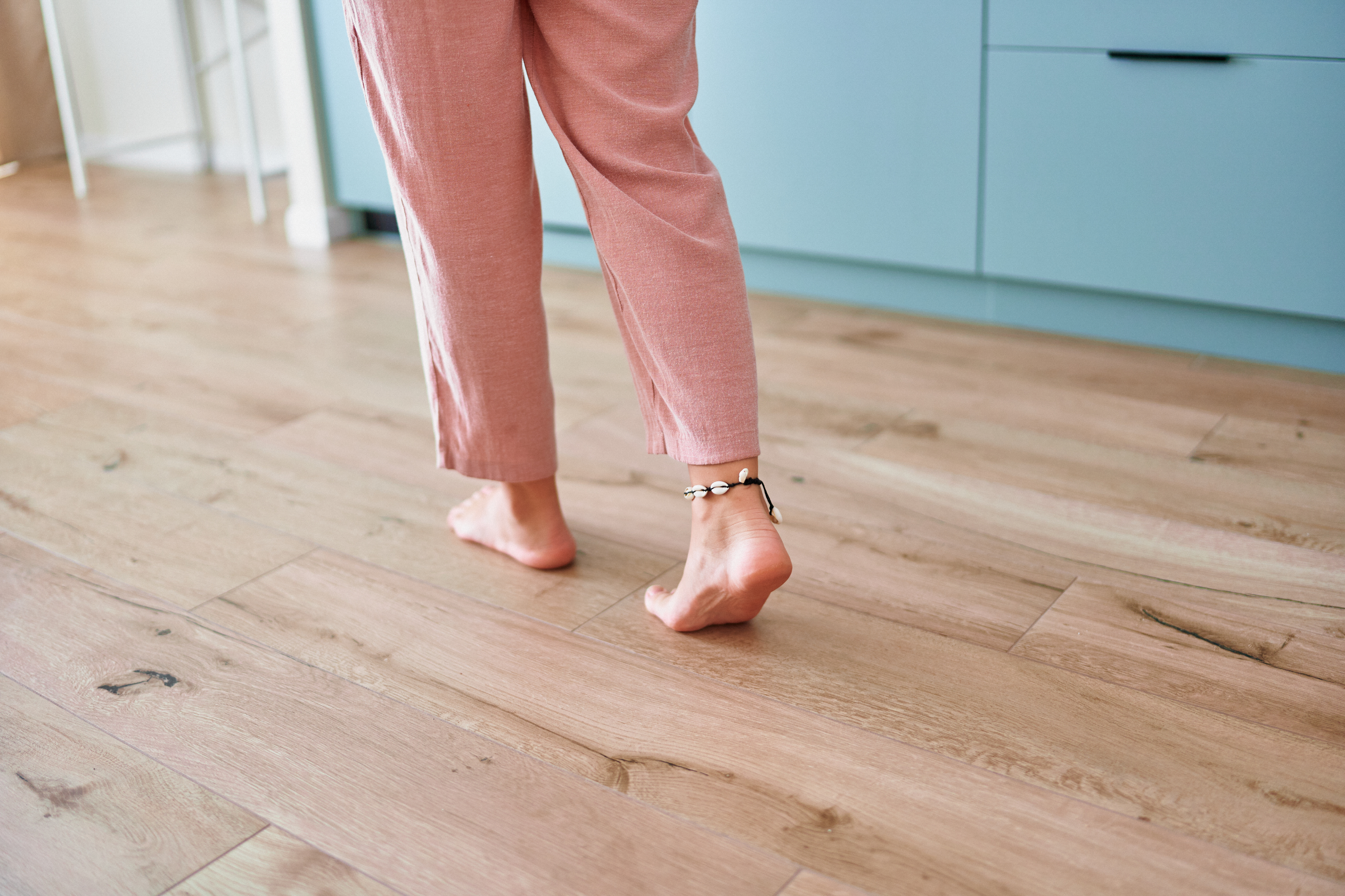 A homeowner walking barefoot across their newly installed laminate flooring from Footprints Floors.