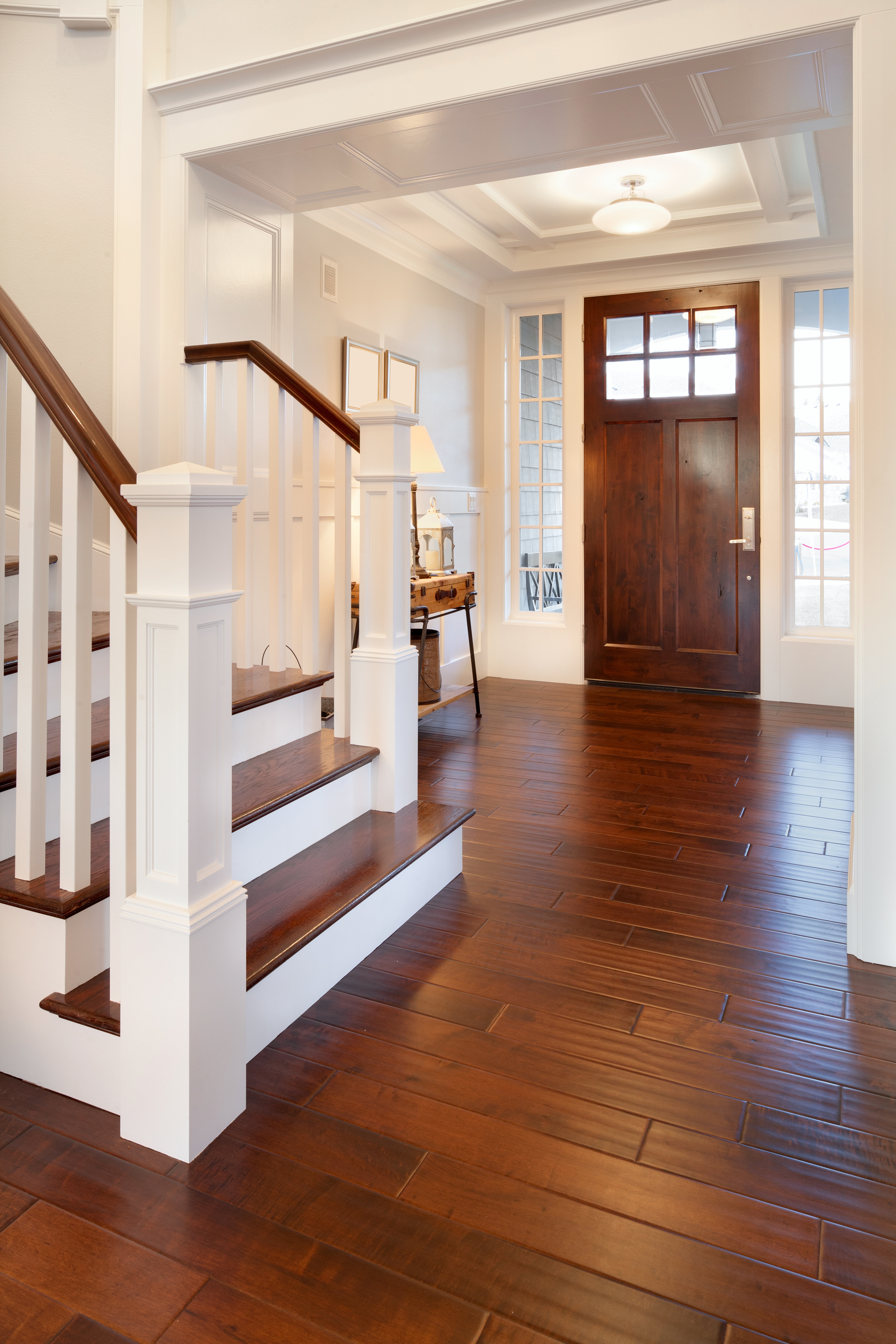 A foyer with hardwood flooring that has a dark finish.