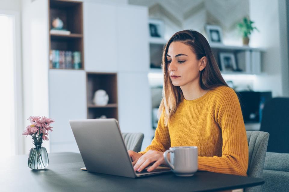 A woman on her laptop looking over the benefits of opening a Footprints Floors affordable franchise.