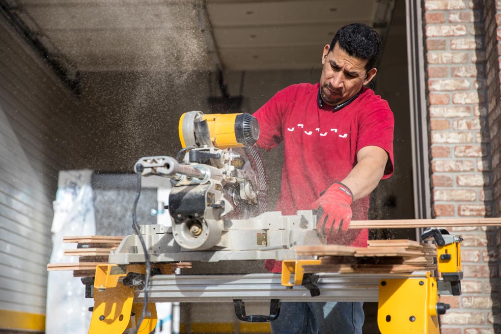 A Footprints Floors worker cutting materials for a project - if you're ready to work on starting a flooring business, contact us today.