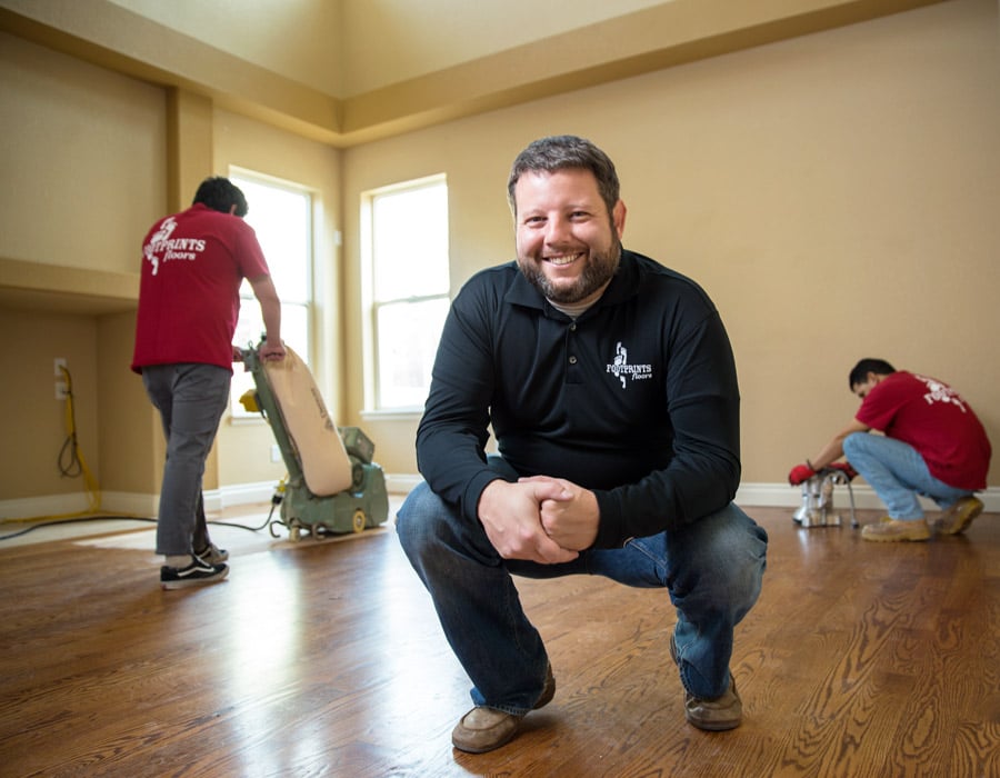 Bryan Park, the found of Footprints Floors, with contractors working behind him on a residential refinishing project.