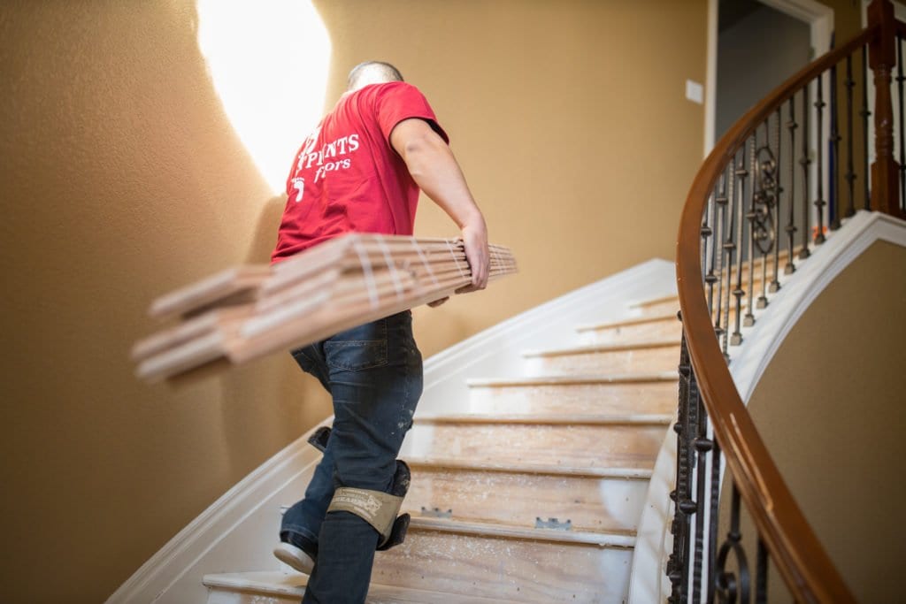 A Footprints Floors team member bringing flooring up stairs in a home - for information on a flooring company for sale, contact us today.
