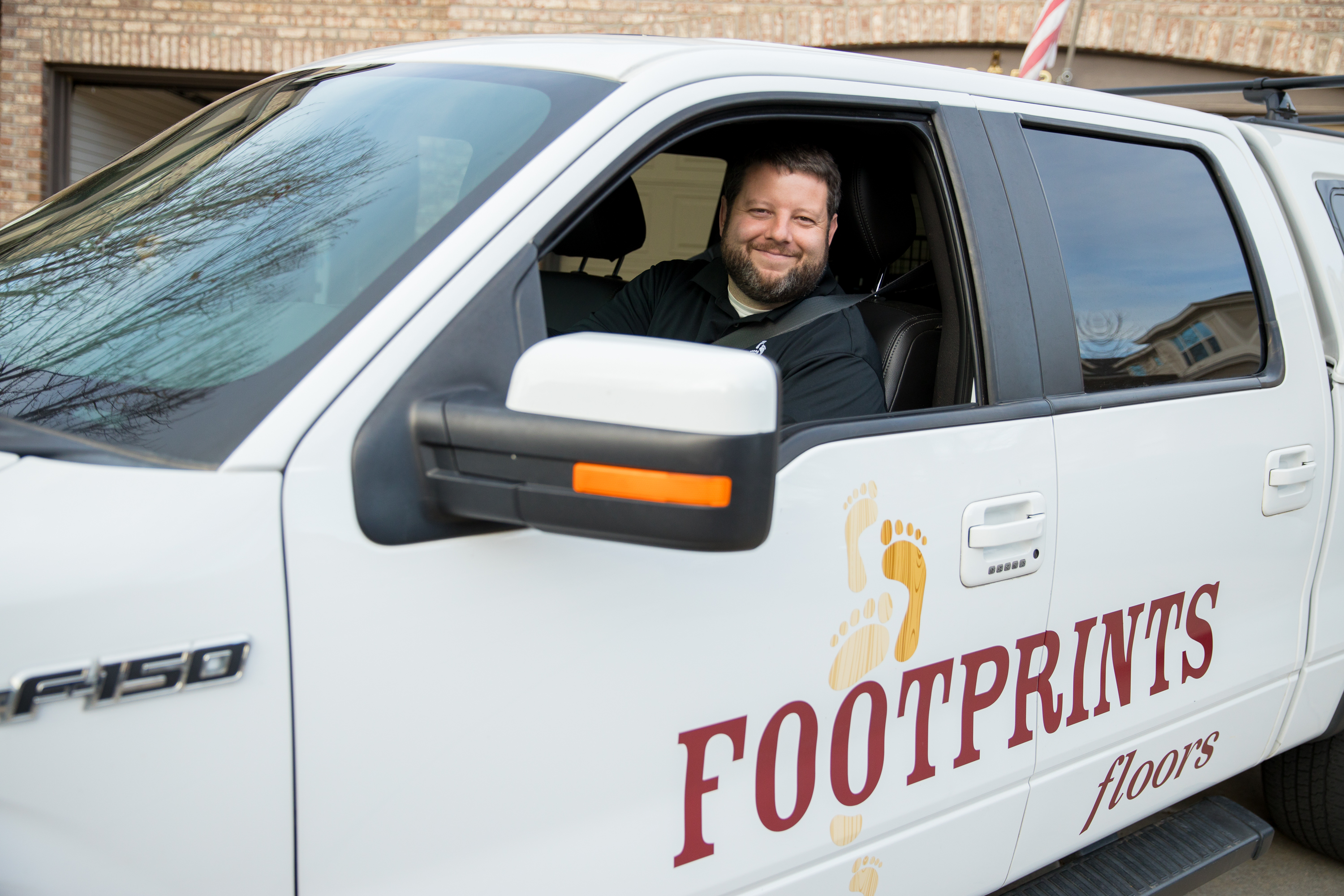A Footprints Floors franchisee sitting in the cab of a company truck.