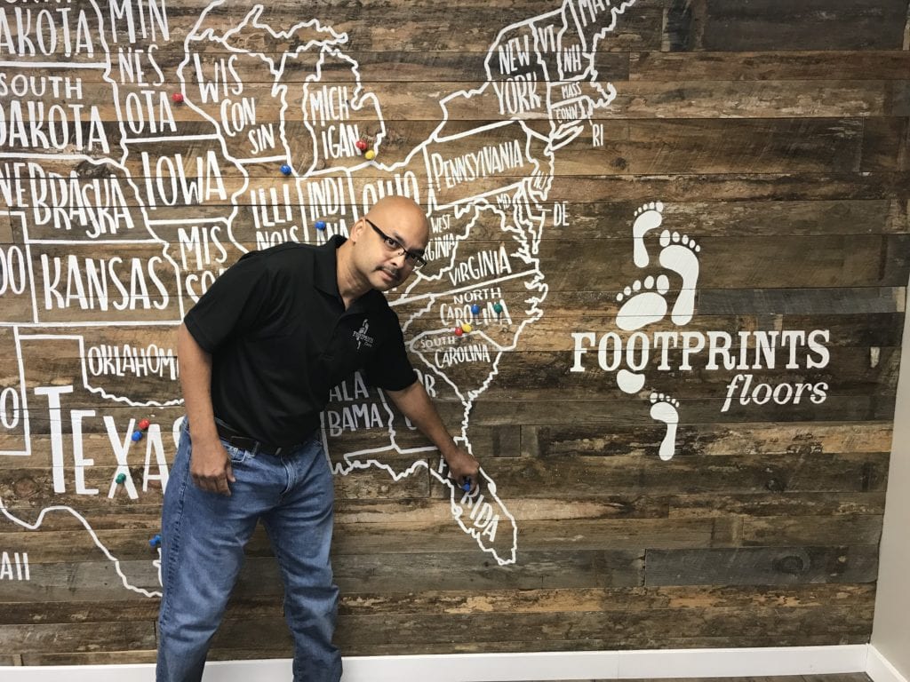 Floyd Khemai standing in front of the Footprints Floors franchise map