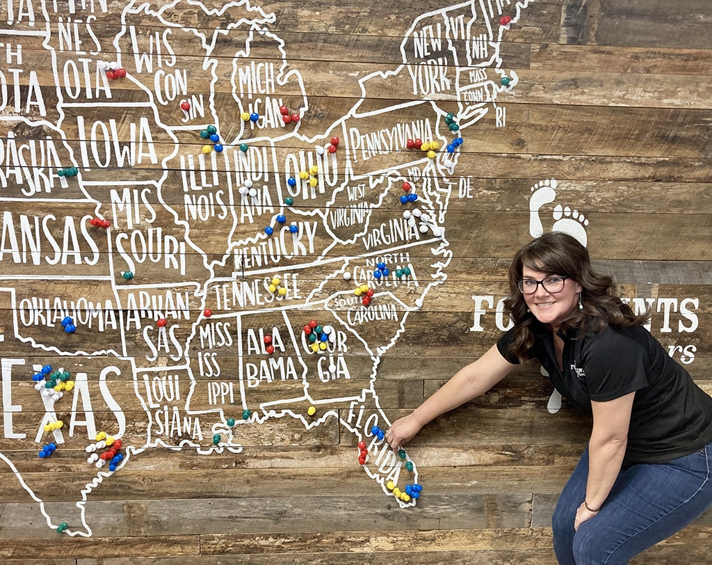 An image of Mandye Tovias standing in front of the Footprints Floors map of franchises. 