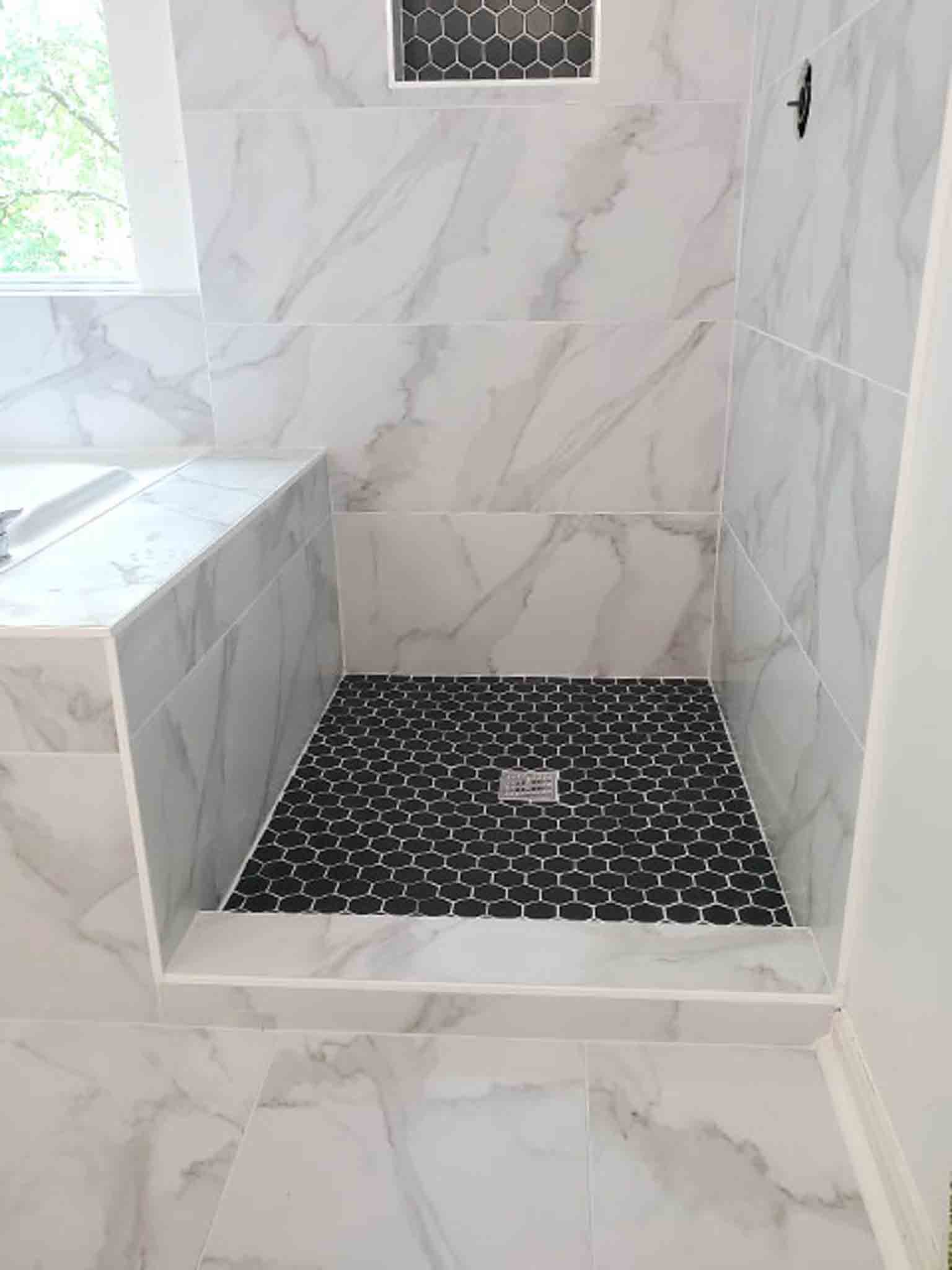 A white stand up shower with black tiling, installed Footprints Floors South Sacramento.
