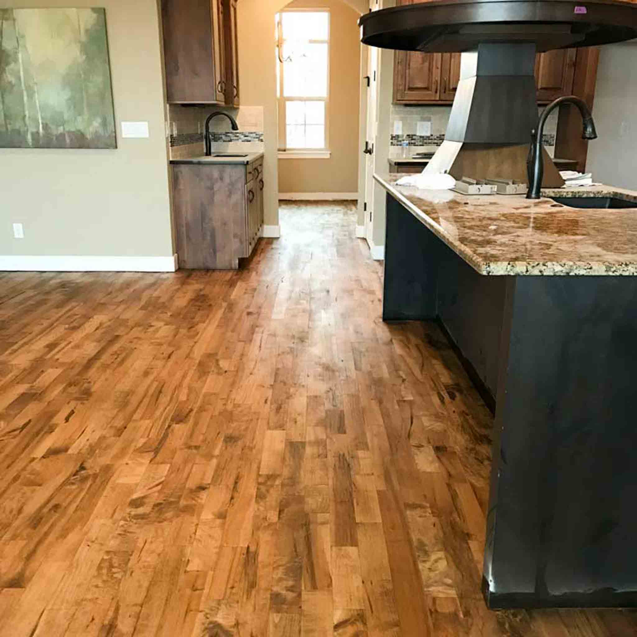 A kitchen with black cabinets and light wood flooring.
