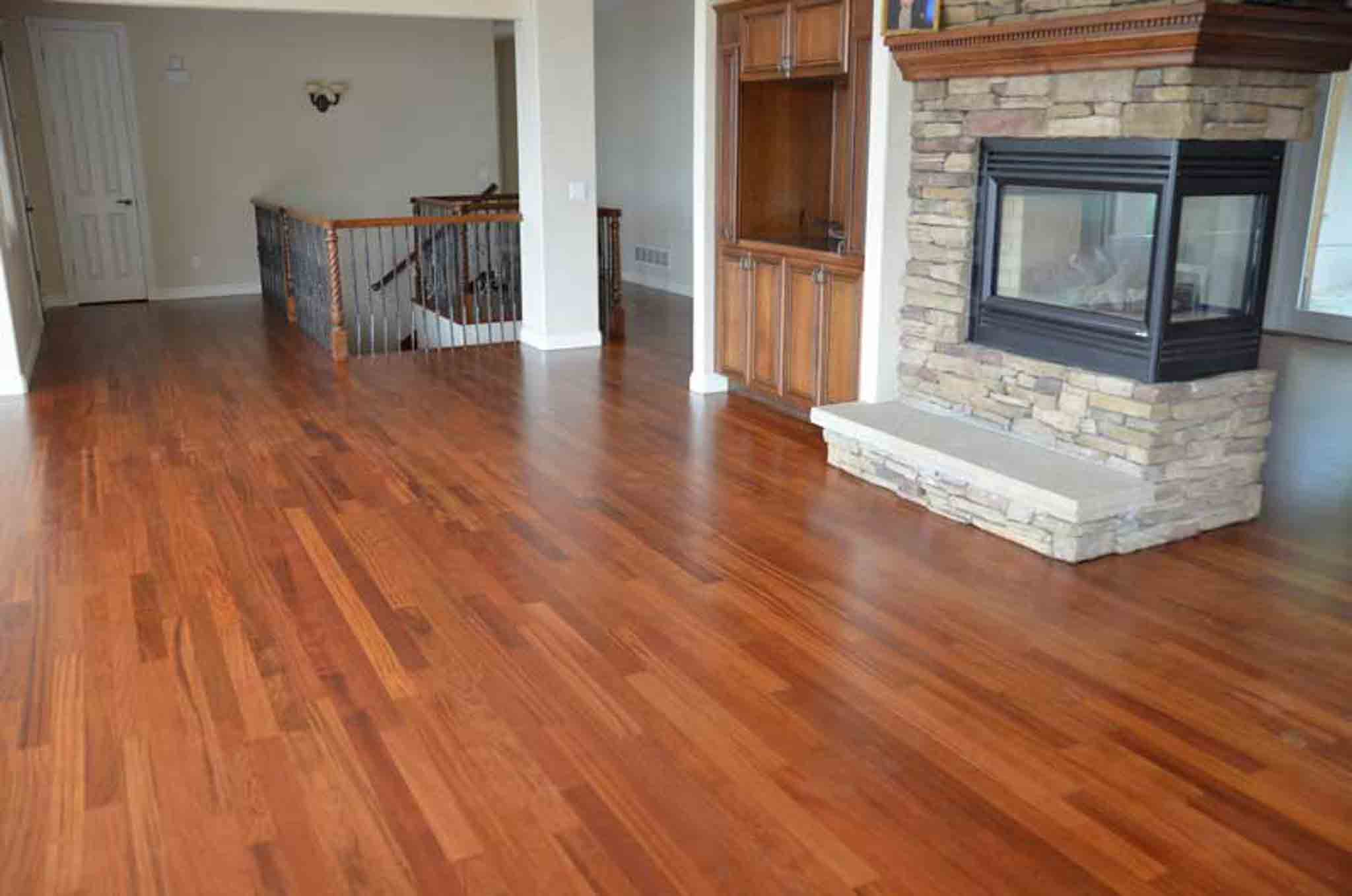 A dark brown wood floor with a stone fireplace in the room.
