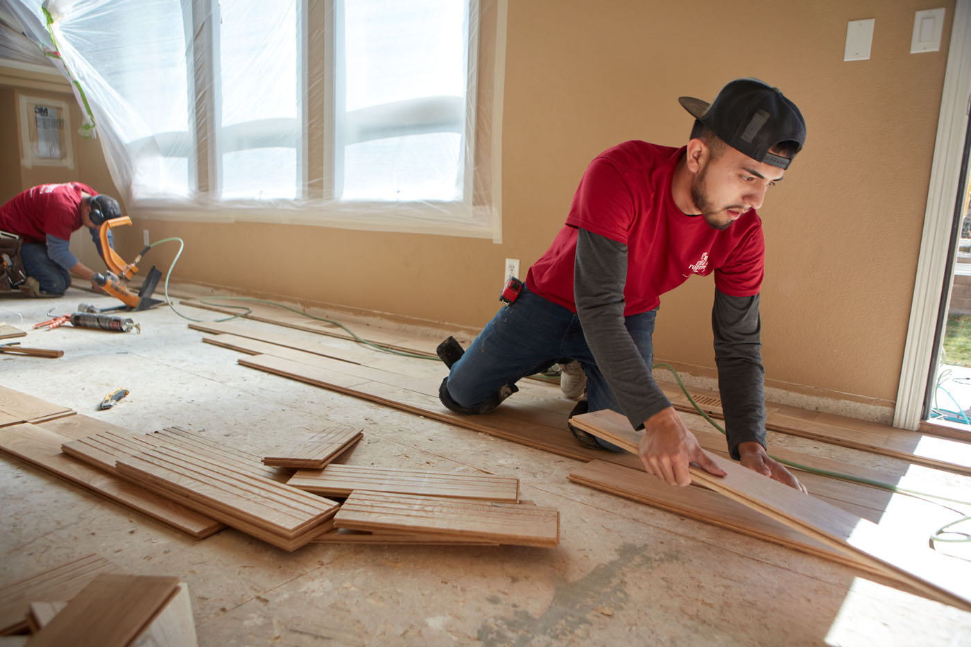 A technician from Footprints Floors, a top hardwood flooring franchise, installing top-quality hardwood flooring.