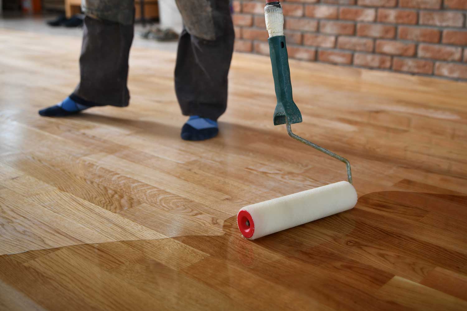 A Footprints Floors Clearwater/Spring Hill professional applying a water-based finish to hardwood flooring.