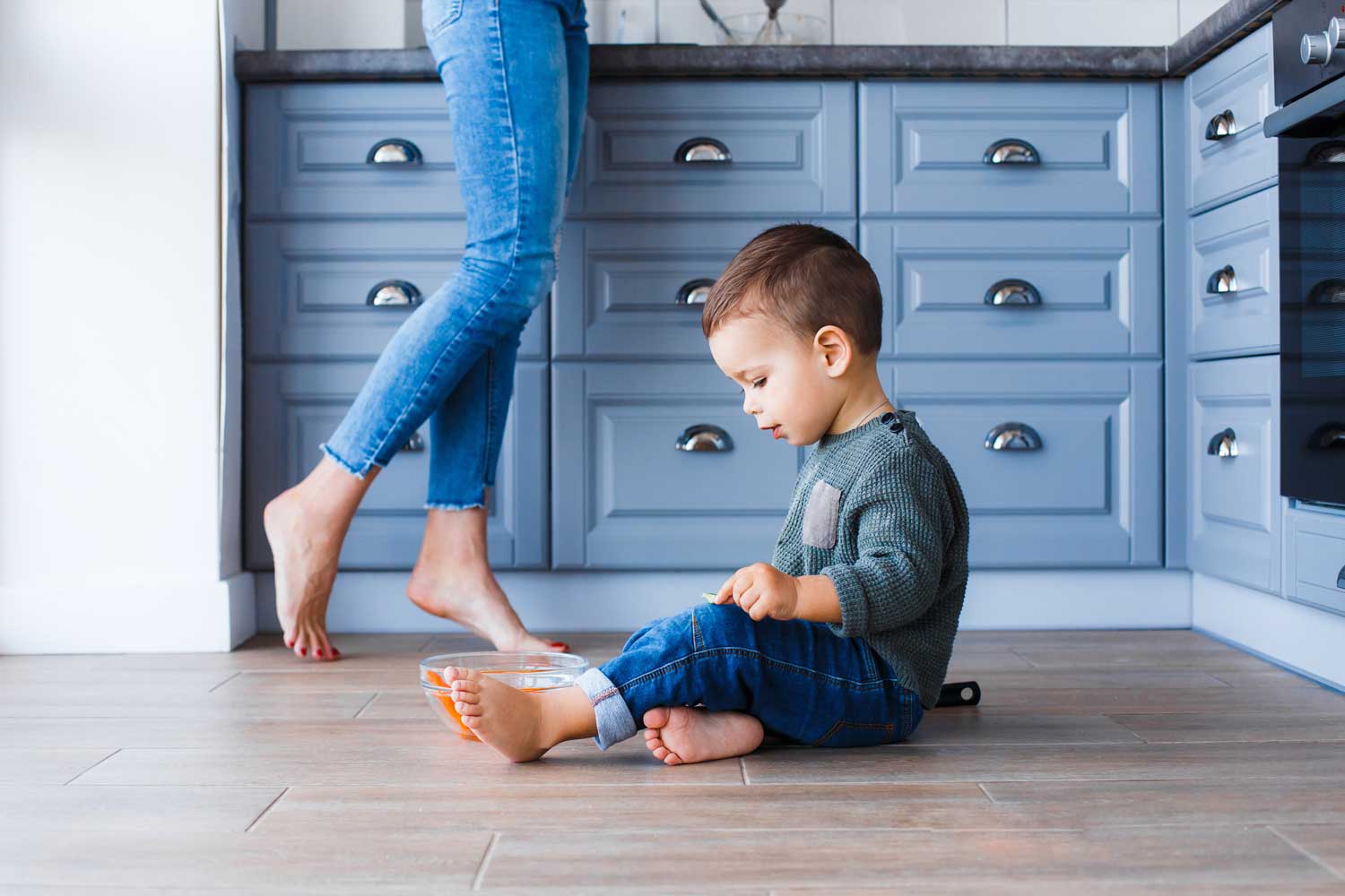 A kid sitting on a trendy floor style of neutral flooring.