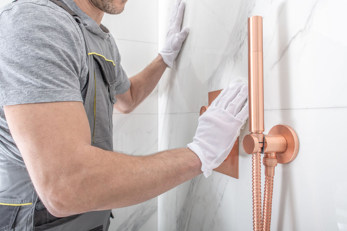 A Footprints Floors contractor putting the final touches with a marbled tile installation in a shower.