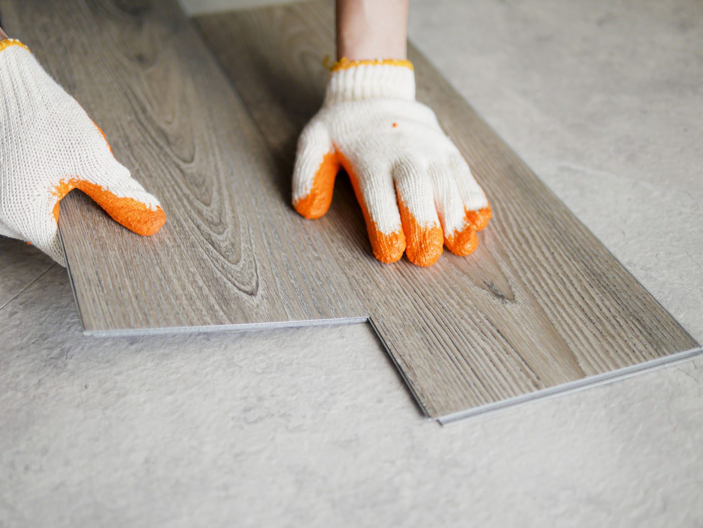 A person in gloves assembling vinyl flooring.