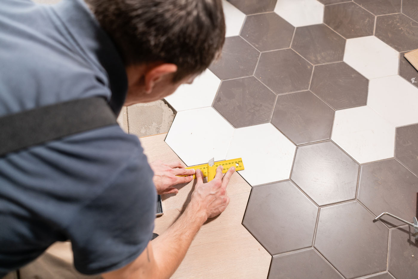 A Footprints Floors contractor installing hexagonal penny tile flooring in a bathroom.