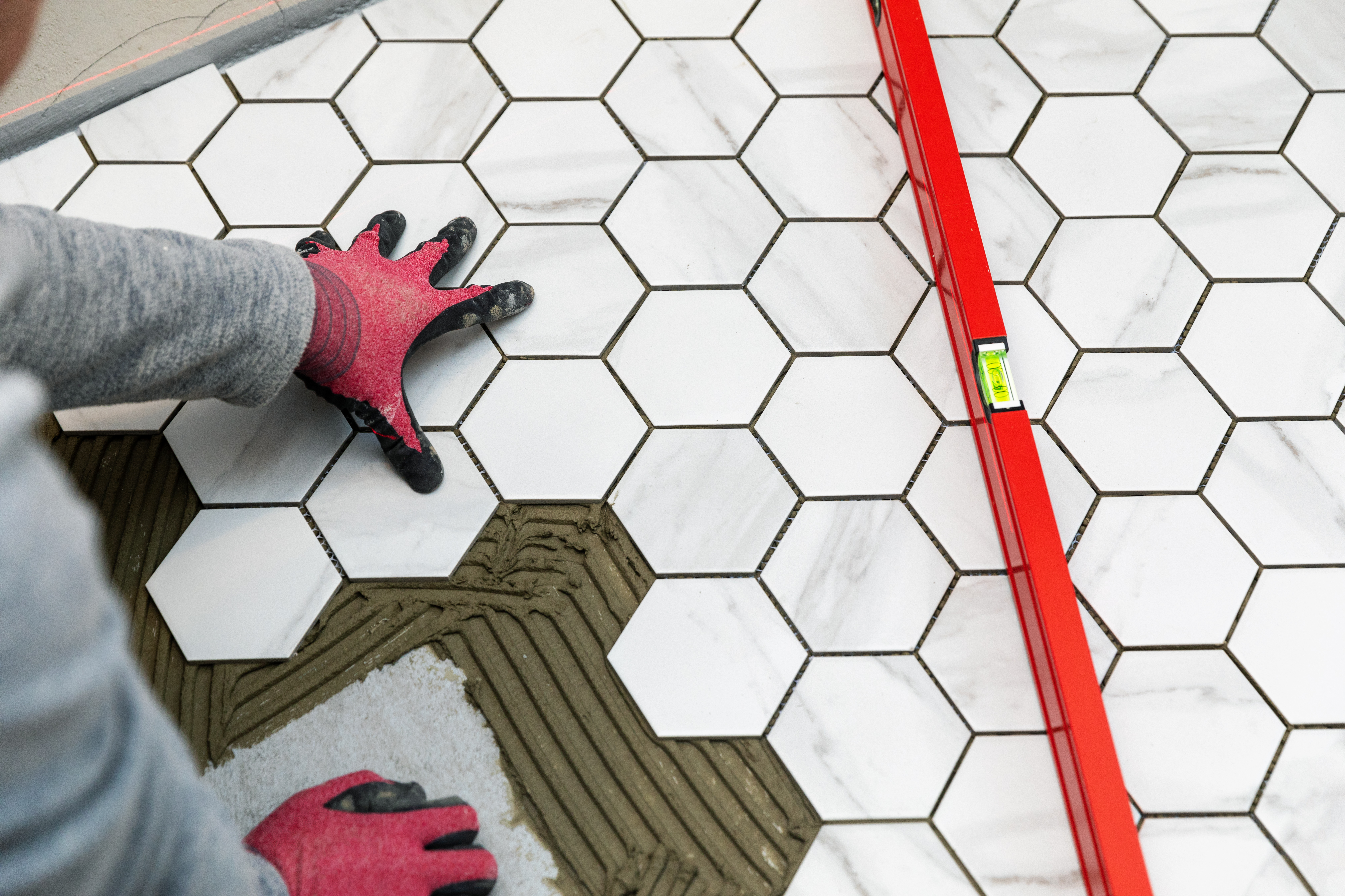 A Footprints Floors contractor finishing a stylish tile installation in a mudroom.