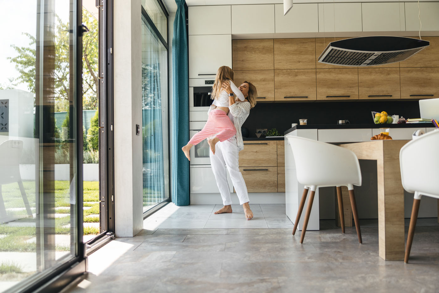 A woman holding her daughter in the kitchen, that has beaitiful tiles installed by Footprints Floors - call today if you are in search of Sacramento tile installers.