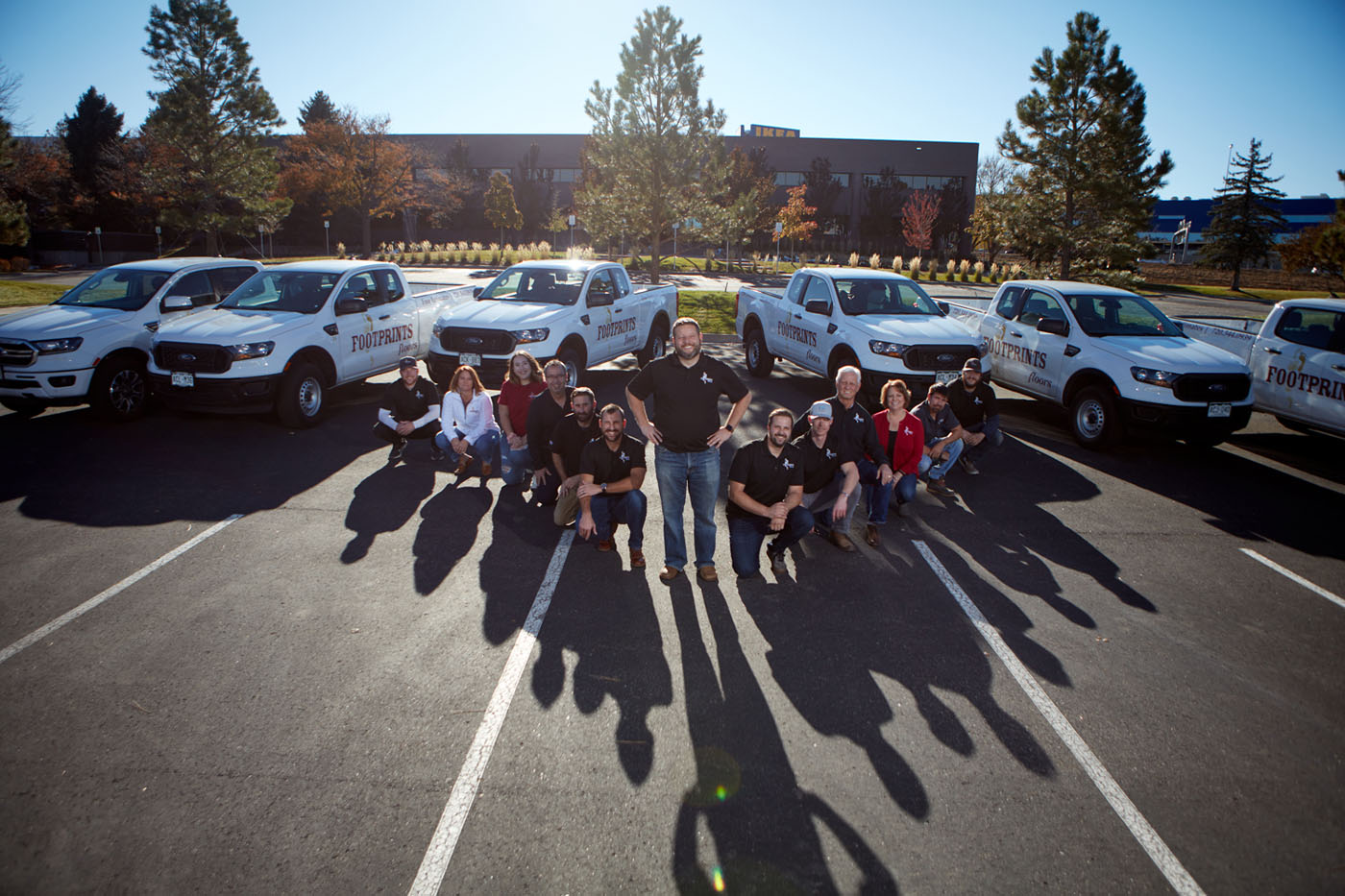A group of Footprints Floors professionals in front of multiple service vehicles.